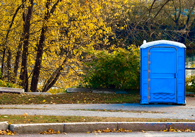 portable toilet out doors at a park near a trail